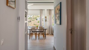 Un área de comedor con una mesa y sillas, vistas al exterior y una puerta que da a otra habitación.