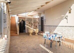 A covered outdoor area with a tiled floor, a table with magazines, and two large urns. - Loft Quiete - Terrazza, Comfort e Silenzio Vicino Alla Spiaggia (Porto Cesareo)