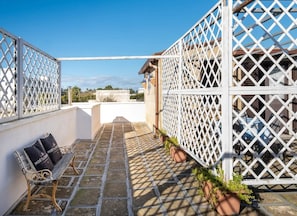 A rooftop patio with a white lattice fence, a bench, and potted plants. - Loft Quiete - Terrazza, Comfort e Silenzio Vicino Alla Spiaggia (Porto Cesareo)