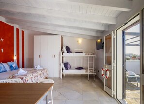 A room with a bunk bed, a desk, a chair, a wardrobe, and a sliding glass door leading to an outdoor area. - Loft Quiete - Terrazza, Comfort e Silenzio Vicino Alla Spiaggia (Porto Cesareo)
