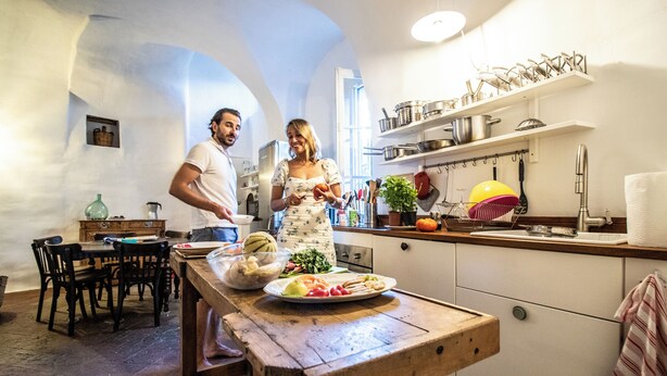 A kitchen with a wooden table, chairs, and a countertop with various kitchen items. - Historic 4BR Village Home | Terrace | Beach 15 min (Ollioules)