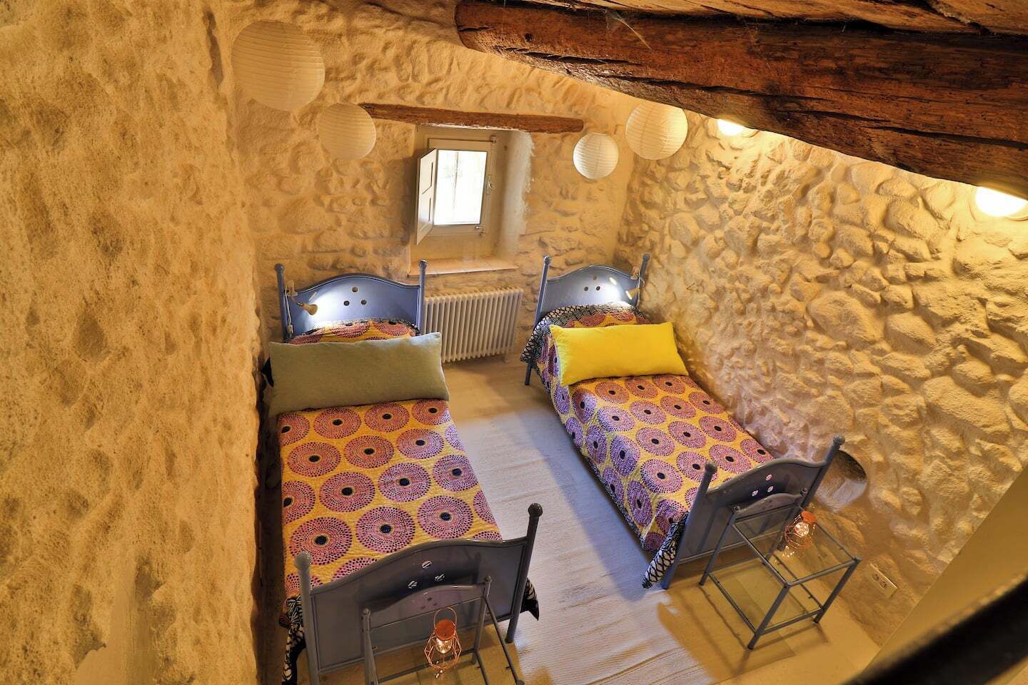 Habitació acollidora amb dos llits, una finestra i parets de pedra.
