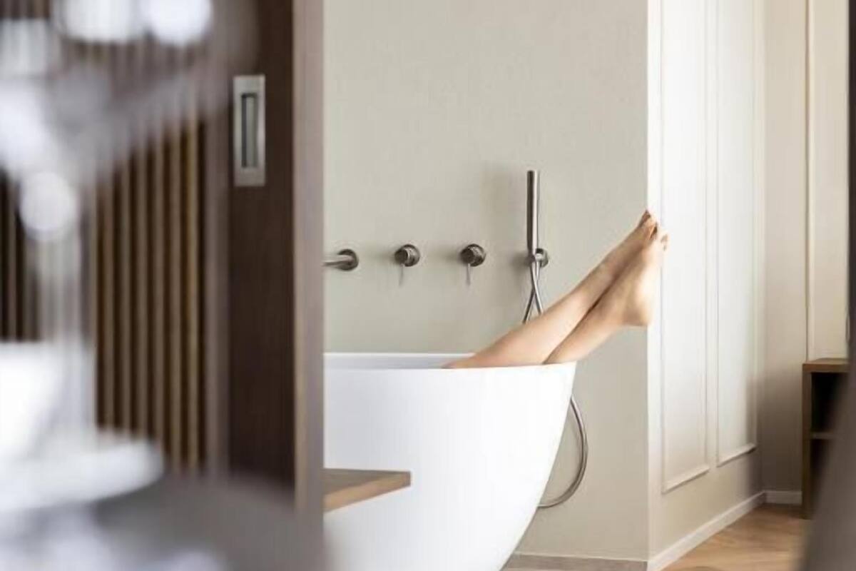 Een moderne badkamer met een vrijstaand bad, een douche en een toilet.