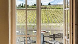 A room with a large sliding glass door leading to an outdoor terrace with a vineyard view. - Lingers Suites & Residence (Appiano Sulla Strada del Vino)