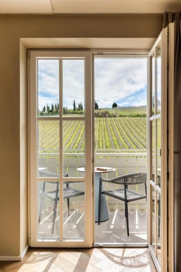 Une pièce dotée d’une grande porte-fenêtre coulissante donnant sur une terrasse extérieure avec vue sur un vignoble.