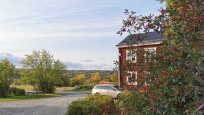 A gravel driveway leading to a red brick building with a car parked nearby. - Spacious Farmhouse – Skiing, Forest & Town. Pet-friendly! (Svenstavik)