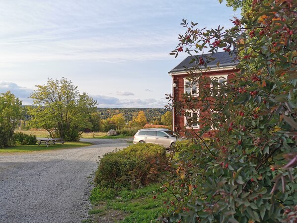 A gravel driveway leading to a red brick building with a car parked nearby.