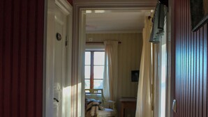A hallway with a wooden floor, a bench, and a door leading to another room. - Spacious Farmhouse – Skiing, Forest & Town. Pet-friendly! (Svenstavik)
