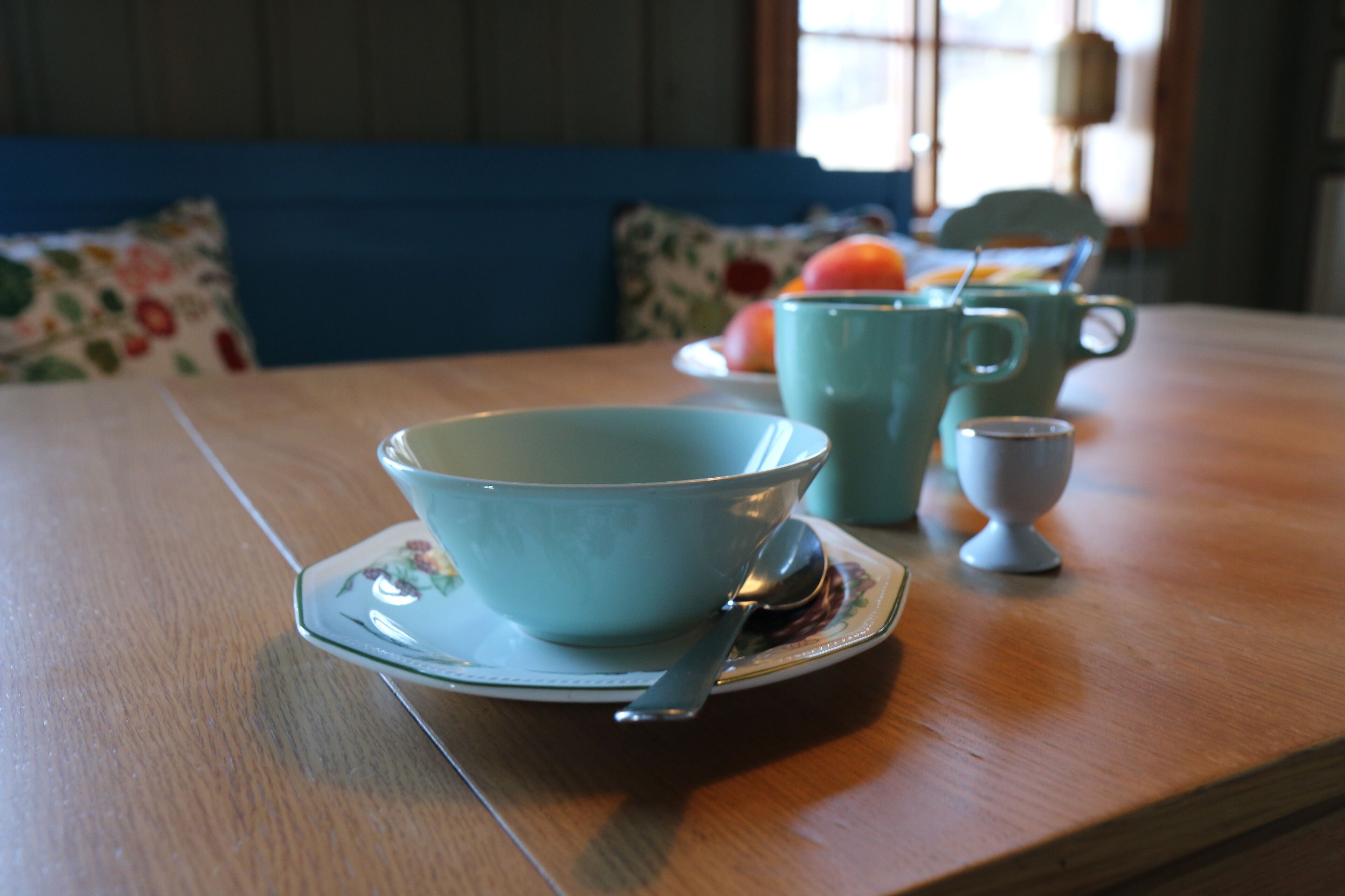 A dining table with a blue bowl and a teapot.