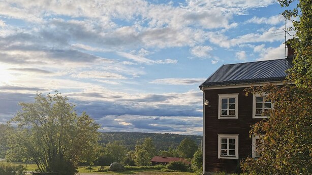 A two-story wooden house with a sloped roof, surrounded by trees and a grassy area. - Spacious Farmhouse – Skiing, Forest & Town. Pet-friendly! (Svenstavik)