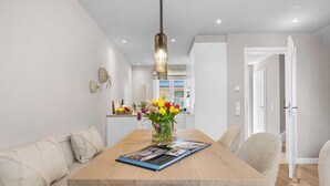 Un comedor con una mesa de madera, sillas, un florero y una lámpara colgante.