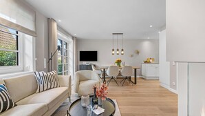 Una sala de estar moderna con sofá, mesa de comedor y zona de cocina.