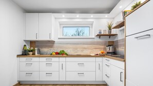A modern kitchen with white cabinets, a wooden countertop, and a window above the sink. - High-quality holiday home in Sankt Peter-Ording with garden (Sankt Peter-Ording)