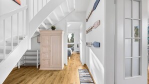 A hallway with a wooden floor, a staircase, a cabinet, and a door with frosted glass panels. - High-quality holiday home in Sankt Peter-Ording with garden (Sankt Peter-Ording)