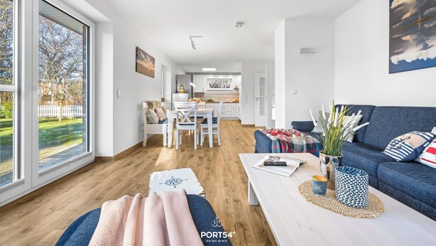 A modern living room with a sofa, coffee table, and a view of a kitchen and dining area. - High-quality holiday home in Sankt Peter-Ording with garden (Sankt Peter-Ording)