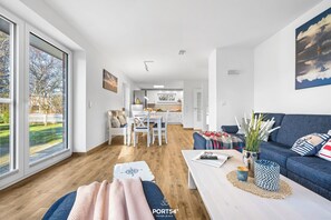Un saló modern amb sofà, taula de centre i vista cap a una cuina i menjador.