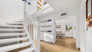 A modern interior with a white staircase, wooden flooring, and a dining area with a view. - High-quality holiday home in Sankt Peter-Ording with garden (Sankt Peter-Ording)