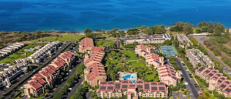 A coastal resort with multiple buildings, a large parking area, and a view of the ocean.