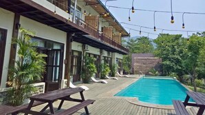 A poolside area with wooden deck, lounge chairs, and a pool. - Landmark Farmhouse (Bharatpur)