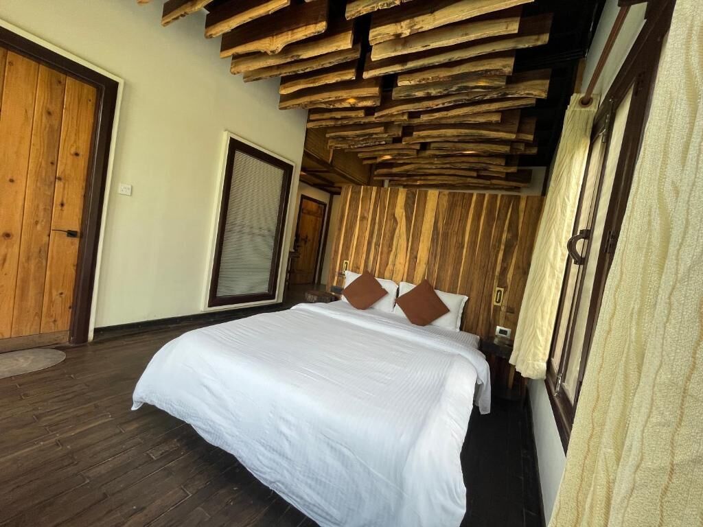 Une chambre à coucher avec une tête de lit en bois, un grand lit avec une literie blanche et un plancher en bois.