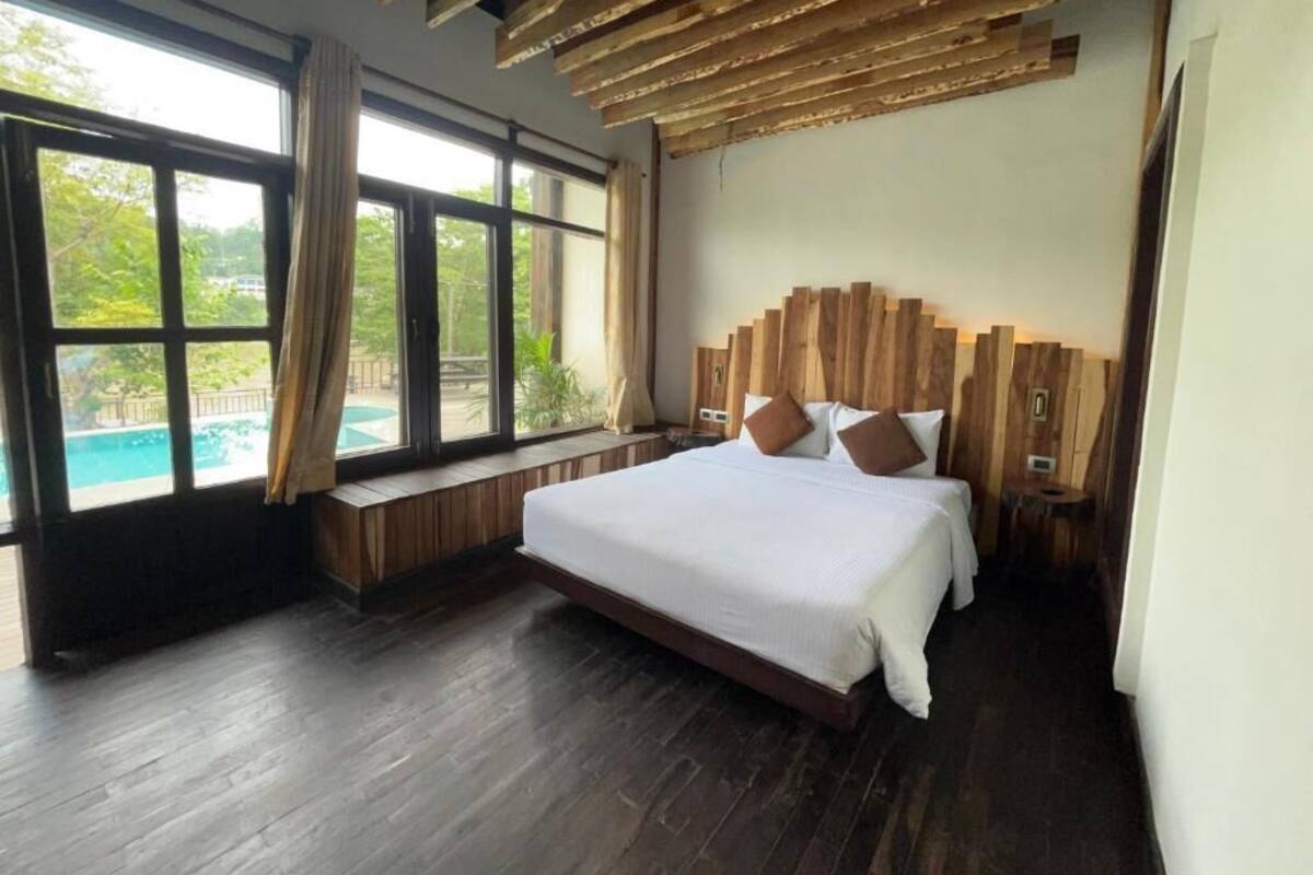A bedroom with a large bed, wooden headboard, and a view of a swimming pool.