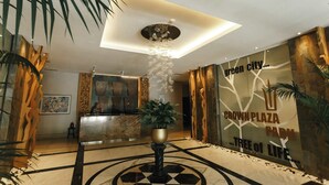 Eine Lobby mit Empfangstresen, einem dekorativen Chandelier und einer Wand mit dem Schriftzug "Crown Plaza Park Tree of Life".