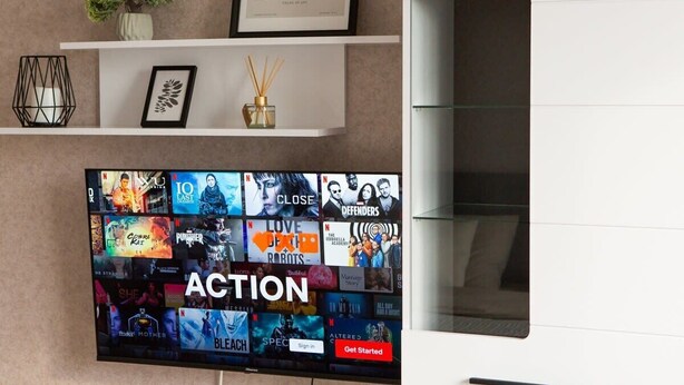 A flat-screen TV mounted on a wall displaying a variety of movie and TV show posters. - Modern&Central | WiFi, Coffee, Netflix | GrandStay (Chișinău)