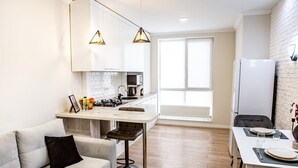 A modern kitchen with white cabinets, a central island, and pendant lighting. - Modern&Central | WiFi, Coffee, Netflix | GrandStay (Chișinău)