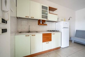 A compact kitchen with white cabinets, a built-in gas stove, and a white refrigerator. - Olive Tree, Borgo Tortorella (Impalata)