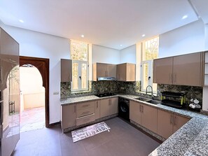 Uma cozinha moderna com bancadas de granito, eletrodomésticos de aço inoxidável e armários cor areia.