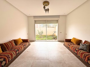 Ein geräumiges Zimmer mit zwei Sofas, die eine Glasschiebetür zu einem Garten hin zeigen.