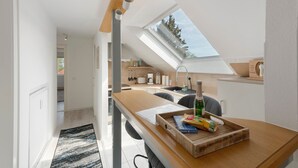 A modern kitchen with a skylight, wooden countertop, and a dining area with a table and chairs.
