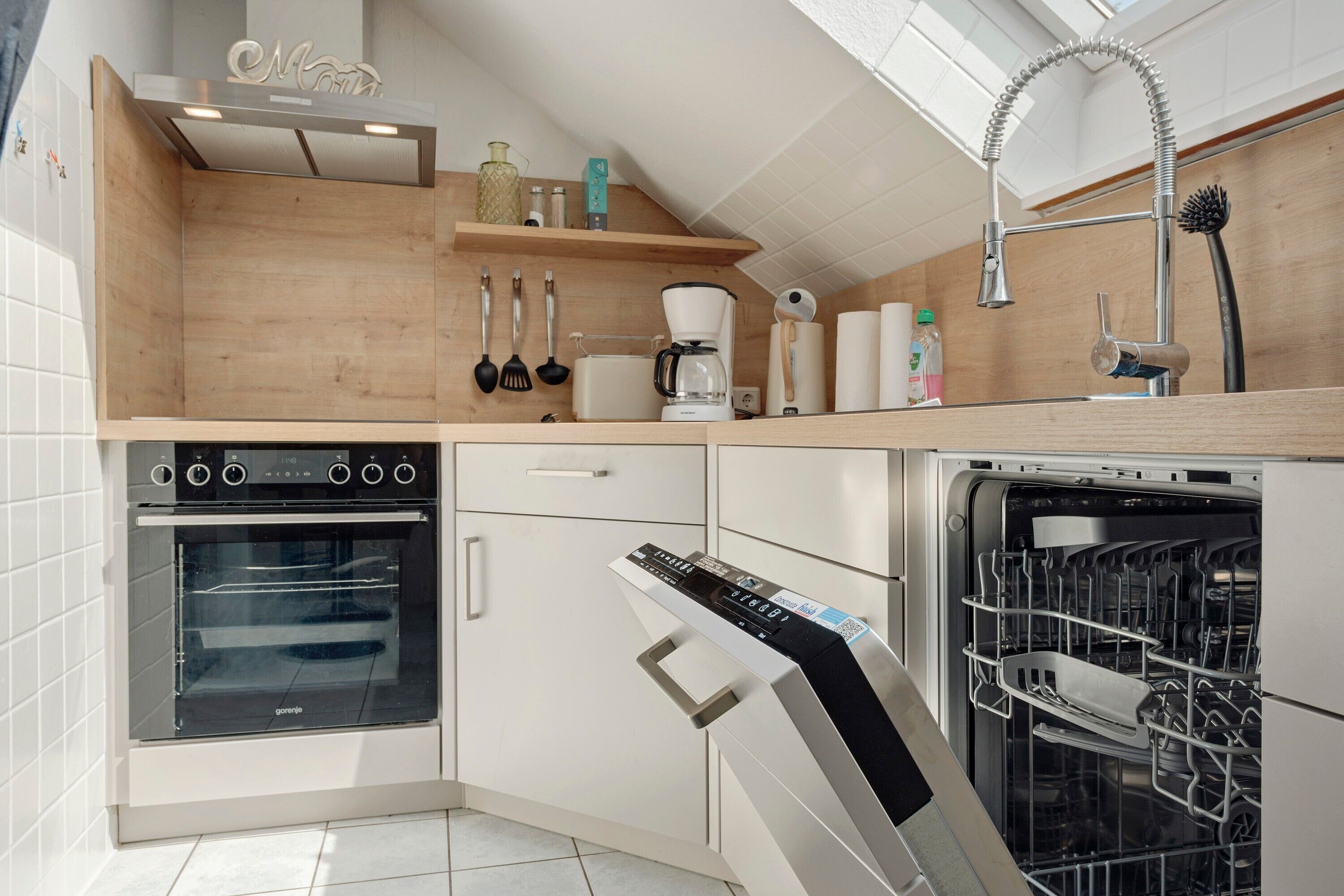 A modern kitchen with a built-in oven, dishwasher, and a coffee maker on the countertop.