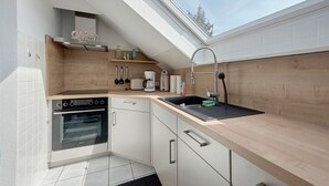 A modern kitchen with a skylight, built-in oven, and wooden cabinetry.