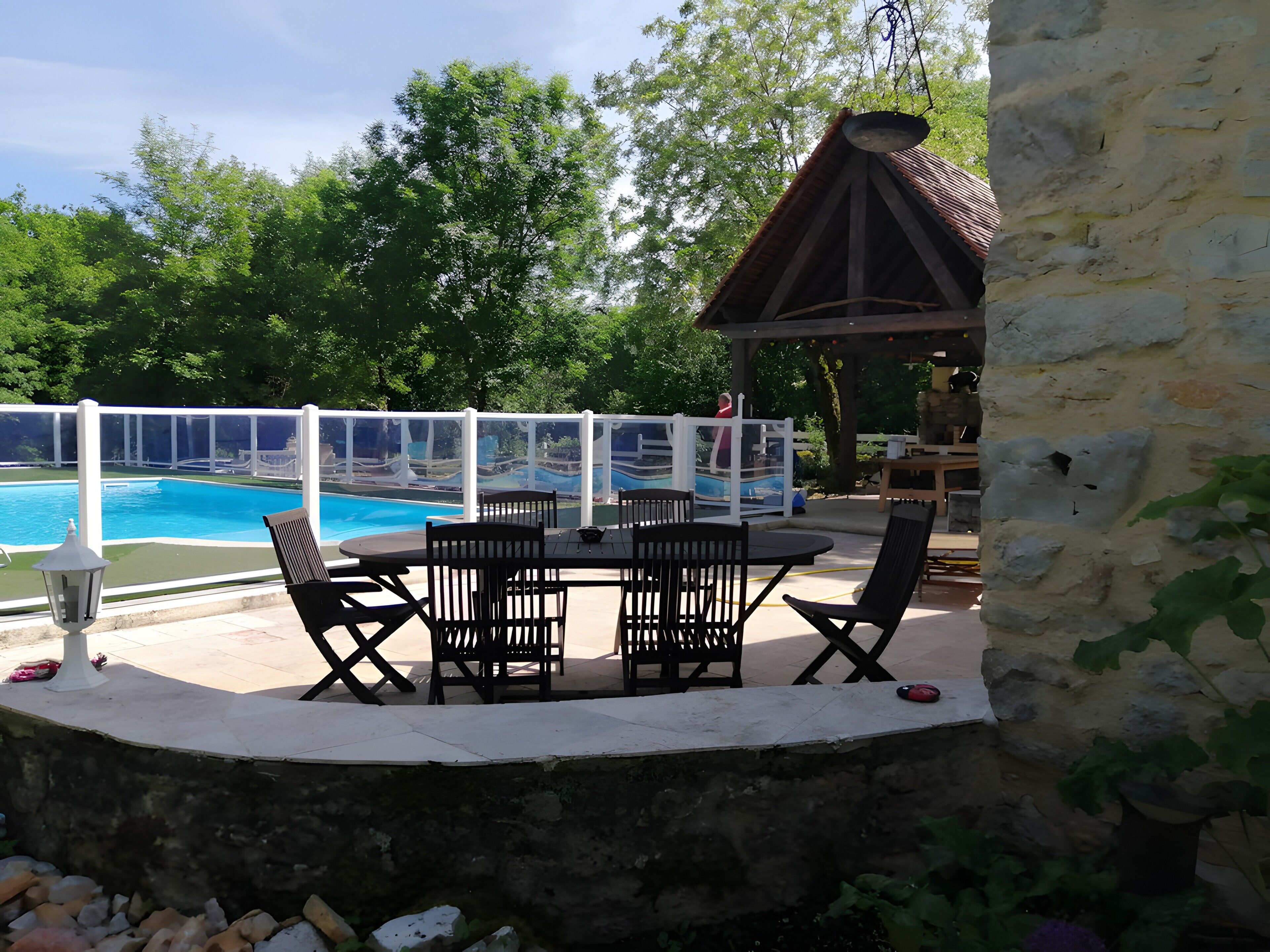 Un espace aménagé au bord de la piscine, avec une table et des chaises, une pergola et une vue sur la piscine.