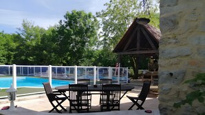 Zona de piscina amb taula i cadires, una pèrgola i vista a la piscina.