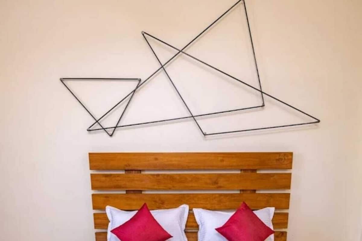 Una cama con cabecera de madera, ropa de cama blanca y almohadas rojas.