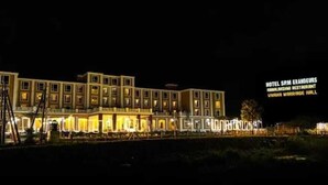 Un hôtel à plusieurs étages, avec des fenêtres illuminées et une enseigne indiquant qu’il comprend un restaurant et une salle de réception pour les mariages.