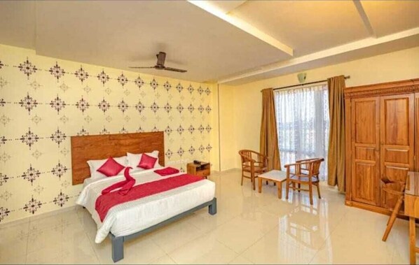 A hotel room with a bed, a desk, and a wardrobe.
