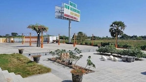 Un hôtel doté d’une grande enseigne, d’un espace extérieur aménagé avec des tables et des chaises, et de plantes en pot.