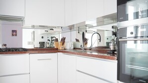Una cocina moderna con armarios blancos, electrodomésticos de acero inoxidable y encimera de granito.