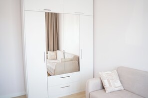 A modern bedroom with a large wardrobe, a bed with a beige duvet, and a light-colored sofa with a patterned pillow. - Designer 2BR Apartment Near Istiklal  Bright & Comfortable Stay (Istanbul)