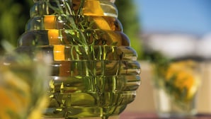 A clear glass container with a layered design, filled with green herbs and yellow flowers, placed on a wooden surface. - 1-bed Apt at Bella Santorini, Near Perivolos Beach (Santorini)