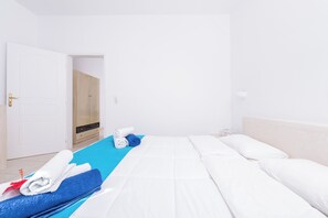 A hotel room with a bed, a blue towel, a white towel, and a wooden door. - 1-bed Apt at Bella Santorini, Near Perivolos Beach (Santorini)