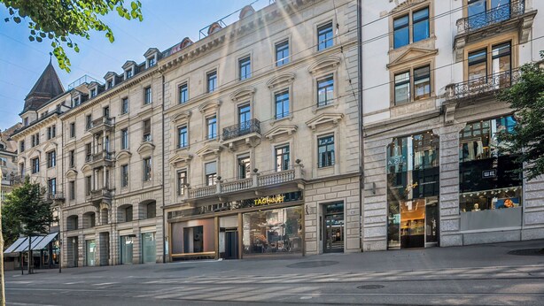 Un edificio de varios pisos con un escaparate que dice 'TAGHeuer' y una entrada visible.