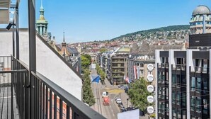 Un paisaje urbano con edificios modernos, una cúpula destacada y una colina verde al fondo.