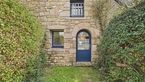 A stone house with a dark blue door and two windows, surrounded by greenery. - Stone house 350m from beach for 4 (Arzon)