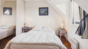 A bedroom with a large bed, two bedside tables with lamps, a window with curtains, and a framed picture on the wall. - Stone house 350m from beach for 4 (Arzon)