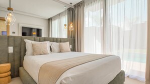 A modern bedroom with a large bed, a television, and two pendant lights. - Bungalow Medina - Heated swimming pool not overlooked (Marrakech)