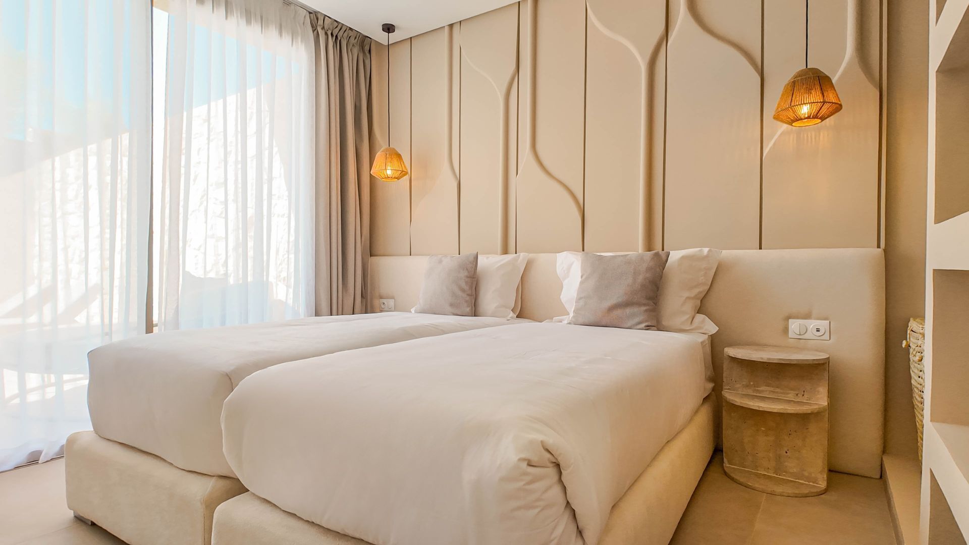 Une chambre d’hôtel avec deux lits, une petite table d’appoint et un luminaire fixé au mur.